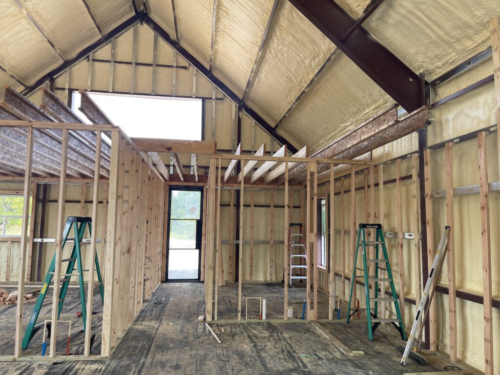 Steel building interior framed out with timber trusses and spray foam