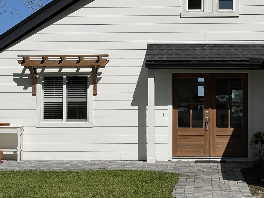 Cedar pergola over a front window beside timber double doors