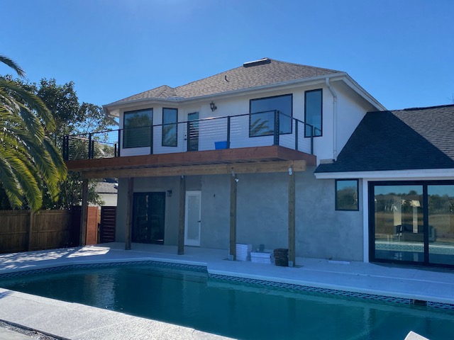 Two story home with cedar columns over a pool deck